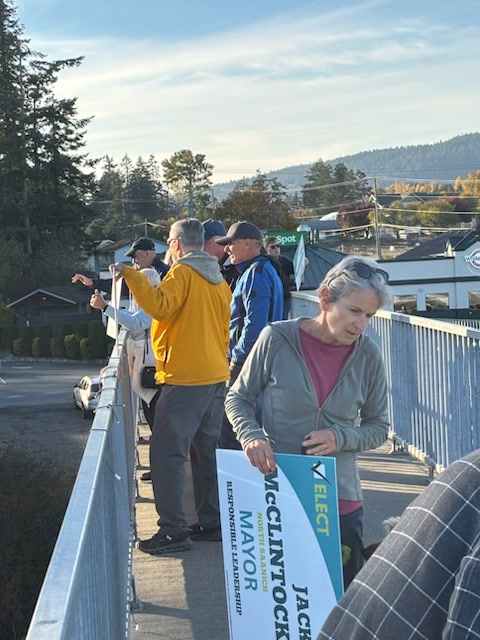 Campaign volunteers with Jack McClintock signs on the pedestrian overpass